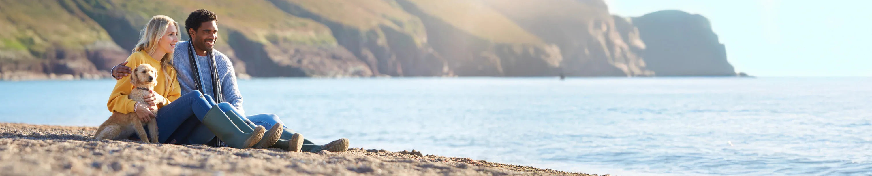 Couple with dog enjoying coastal view, perfect for outdoor adventures and camping trips