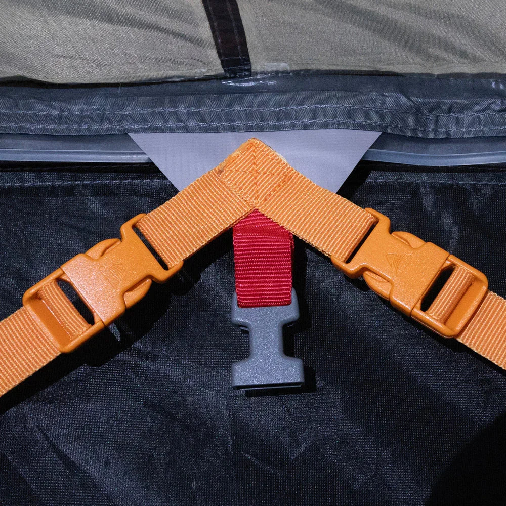 Orange and red straps with buckles on camping gear for secure outdoor equipment setup