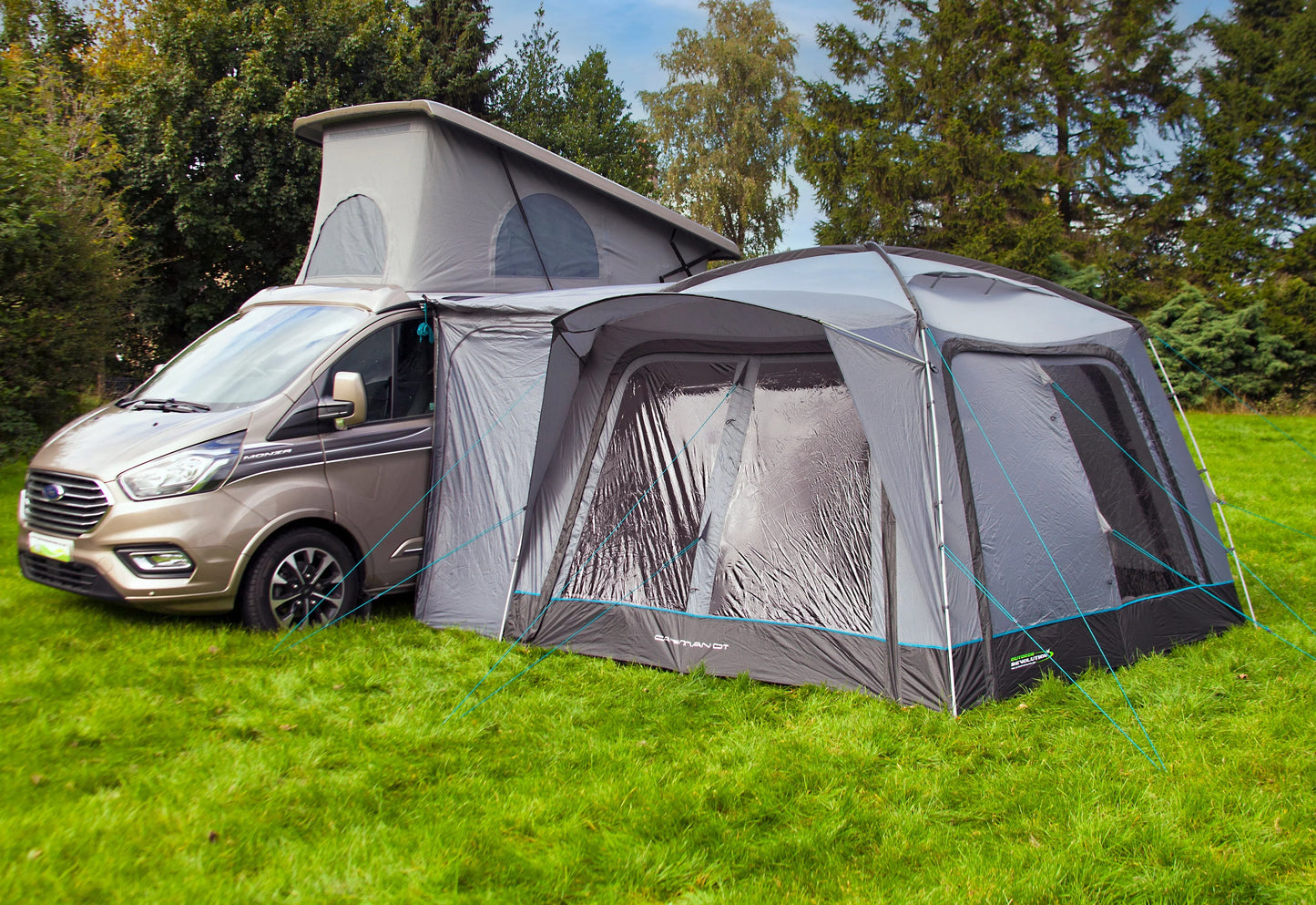 Ford Transit camper van with attached awning on grassy field, ideal for caravanning and outdoor adventures.