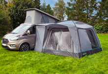 Ford Transit camper van with attached awning on grassy field, ideal for caravanning and outdoor adventures.