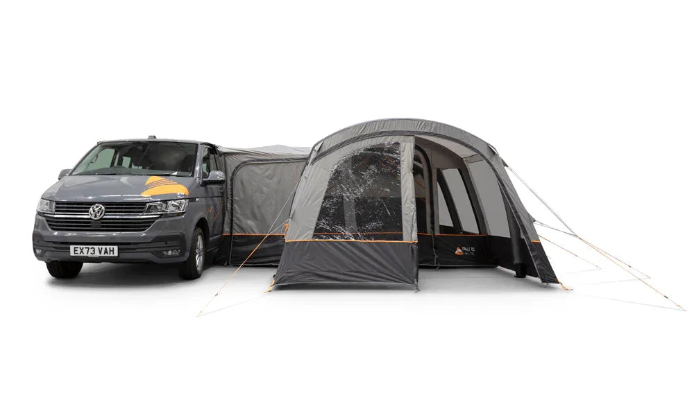 A dark gray Volkswagen camper van towing a large gray and black awning tent with transparent window panels, shown on a plain white studio background.