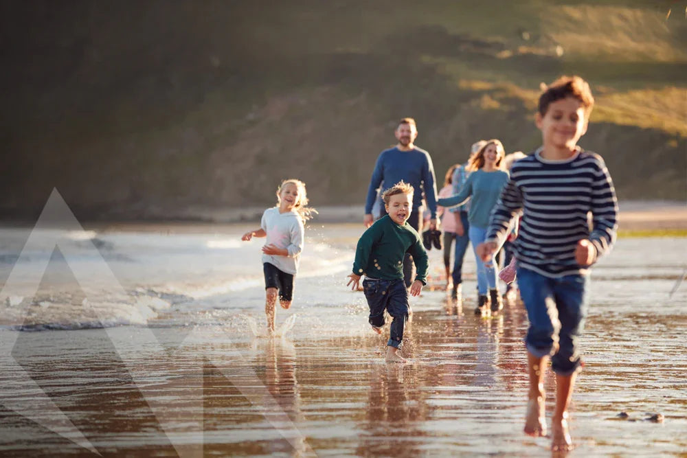 Family running on beach at sunset, enjoying outdoor adventure and leisure time together.