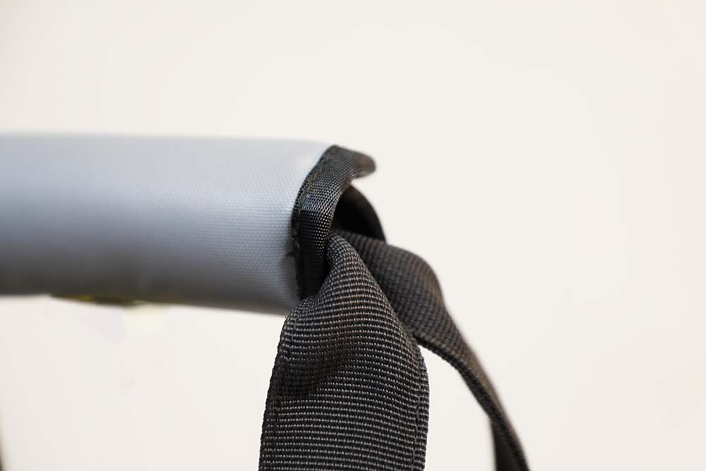 Close-up of a black strap attached to a gray object on a light gray background