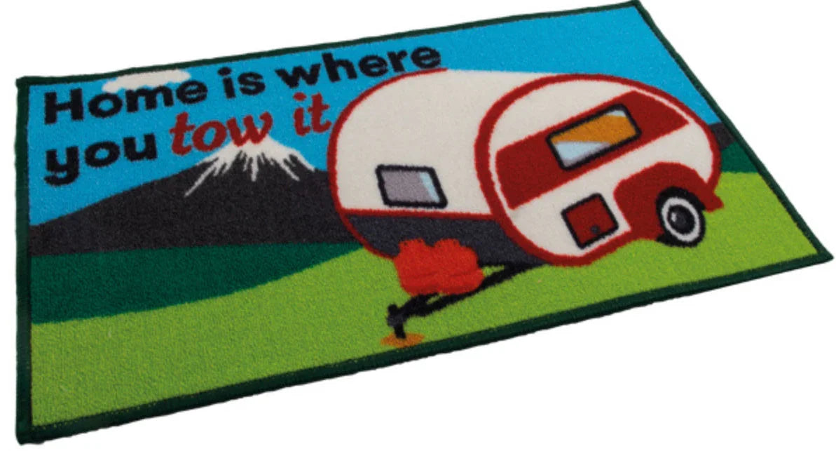 Doormat with a camper design and text 'Home is where you tow it' on a blue background