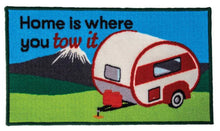 Patch with a camper and 'Home is where you tow it' text against a blue sky and green landscape background.